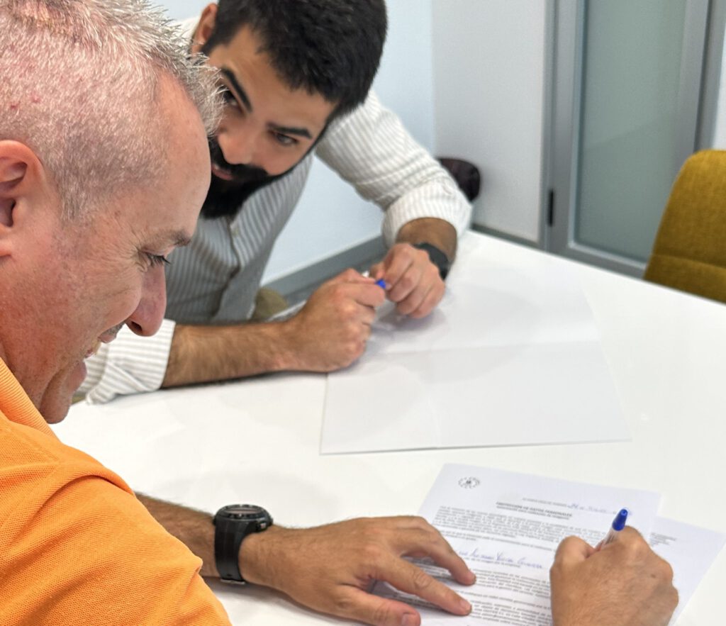 Un cliente firma los últimos documentos de su procedimiento acompañado de su asesor