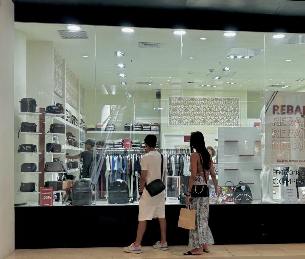 Dos personas mirando el escaparate de un comercio con un cartel de rebajas