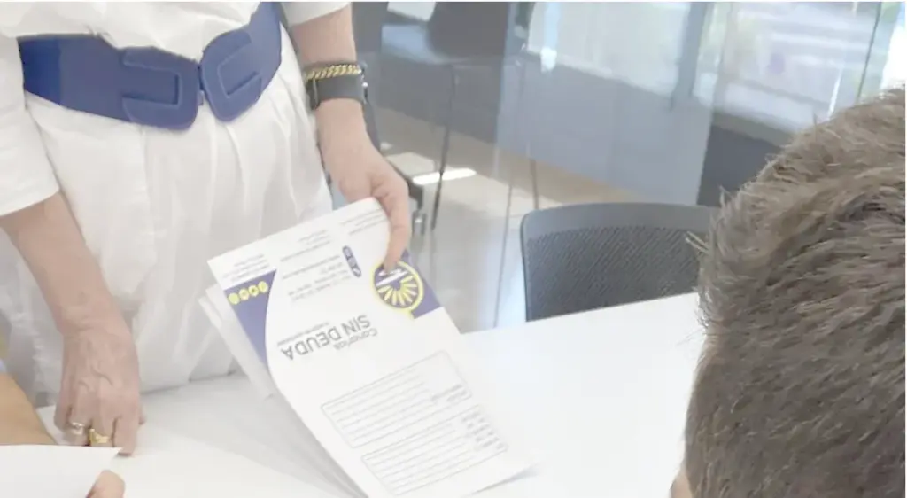 Una asesora muestra una carpeta de Sin Deuda Group a un cliente en una mesa de oficina
