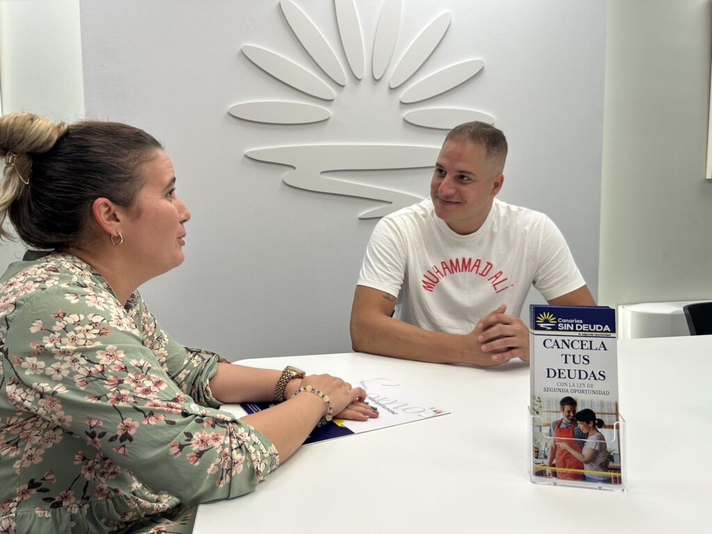 Una abogada y un cliente durante una reunión en la oficina, con el folleto de la Ley de Segunda Oportunidad sobre la mesa