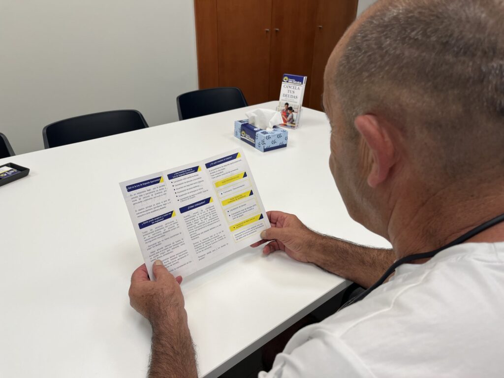 Primer plano de un documento con apartados marcados sobre una mesa, junto al folleto informativo de Sin Deuda Group