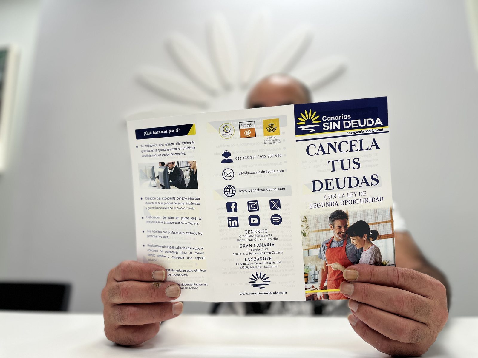 Manos sosteniendo el folleto informativo de Sin Deuda Group sobre la cancelación de deudas y la segunda oportunidad